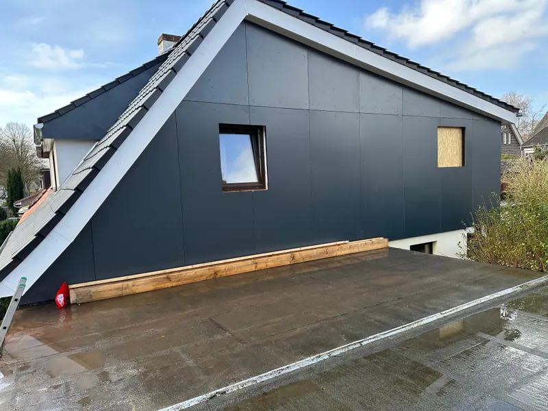 Anbau in Holzrahmenbauweise mit anthrazitfarbener Fassade an einem bestehenden Haus